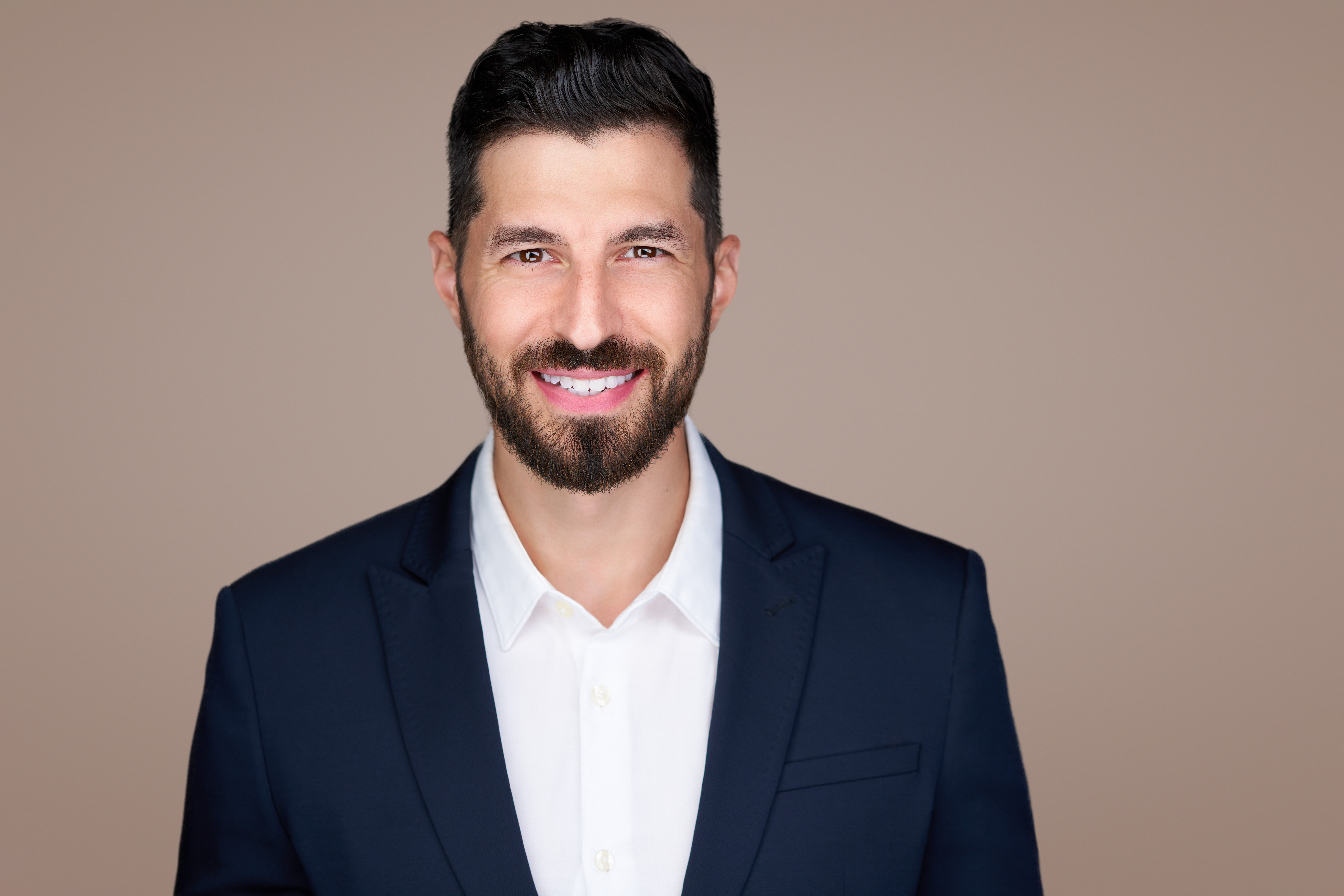 John-Michael Perez, MD, smiling in a navy suit